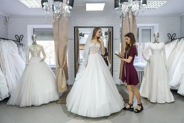 Продавец Помогает Молодой Невесте Свадебном Салоне — стоковое фото
