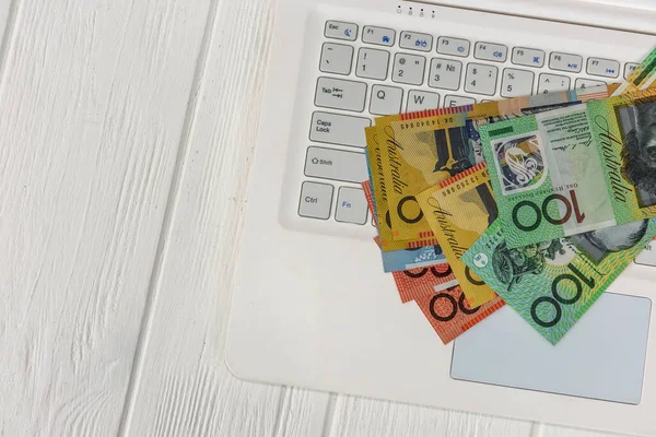Australian dollar banknotes on white laptop keyboard