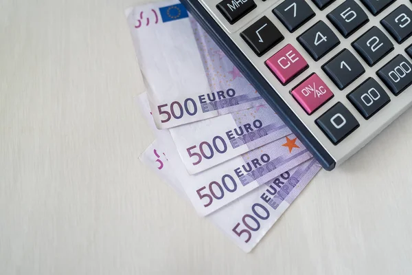 Tahta masanın üzerinde hesap makinesi olan Euro banknotları