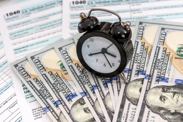 American dollars with clock over individual tax form