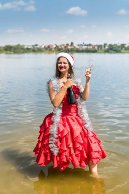 Bir şişe şampanyası olan kadın suyun içinde duruyor.