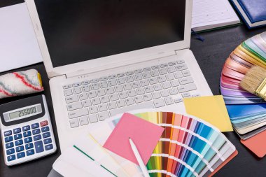 Masanın üzerinde renk örnekleri olan dizüstü bilgisayar kapat