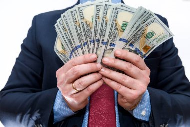 Takım elbiseli adam dolar banknotlarını tutuyor.