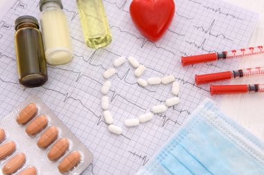 İlaçlar ve şırıngalarla kardiyogramda beyaz haplar