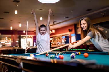 Mutlu ve heyecanlı kadınlar bilardo oynuyorlar.