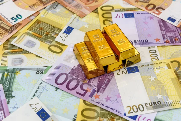 Gold bullions at euro banknotes background closeup