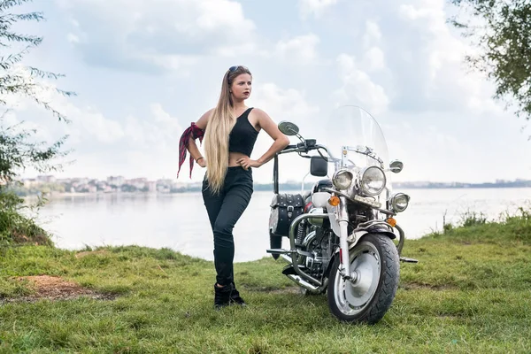 Beautiful woman posing with helmet and motorcycle