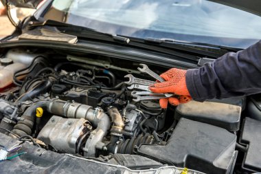 Araba motorunda çelik anahtarı olan bir erkek.