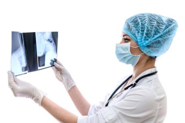 Cerrah beyaz arka planda hastanın röntgenini inceliyor.