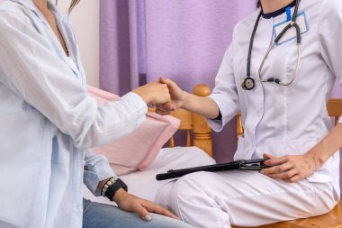 Hastaneyi ziyaret ediyorum. Hasta ve doktorun kadın tokalaşması. Kapatın.