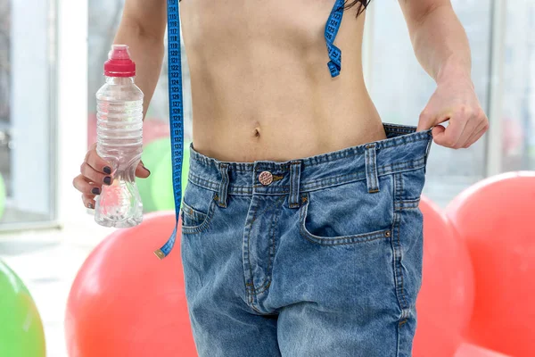 Woman's belly in oversized jeans close up