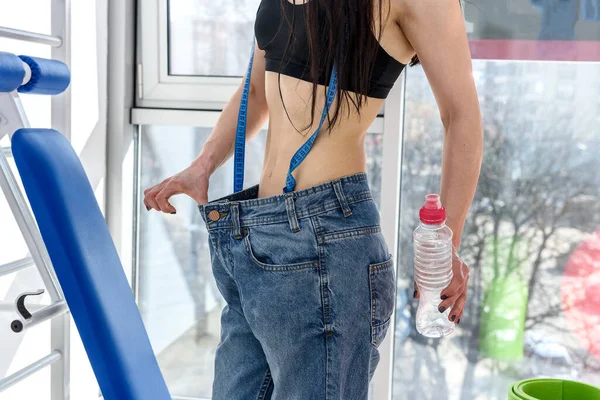 Woman\'s belly in oversized jeans close up