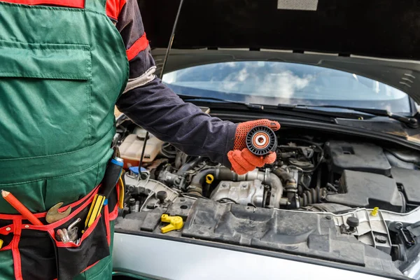 Mechanic with tool belt showing car filter against car engine close up