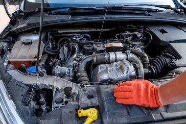 Araba motoruna karşı yağ sayacı olan insan elleri