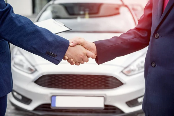 Male hands against car, making handshakes close up