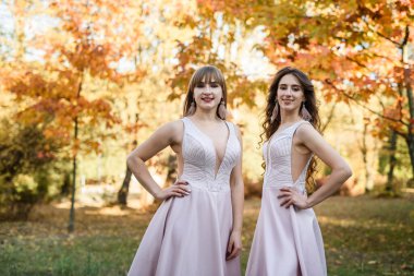 Sonbahar parkında güzel bej elbiseler giyen iki genç prenses. Moda fotoğrafı..