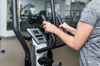 Egzersiz bisikletleriyle bisiklet sürmek. Kız spor salonunda egzersiz bisikletiyle meşgul. Kapat.