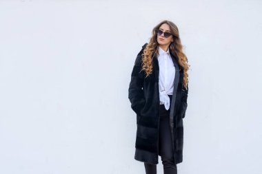 Dışarıda poz veren kürklü ve güneş gözlüklü moda kadını.