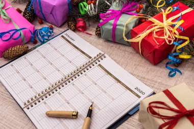 Kalem ve renkli hediye kutularıyla dolu bir not defteri. Kutlama ve hediyeler