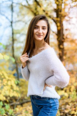 Sonbahar parkında sıradan giyinmiş esmer kadın portresi. Güzel bir kadının etrafında sarı renkler