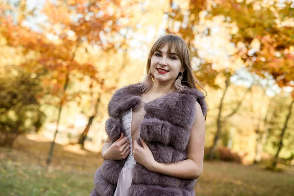 穿着毛皮外套的时尚女装和在秋季公园摆姿势的服装 — 图库照片