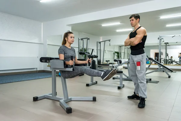 Woman in gym making exercises for belly on equipment