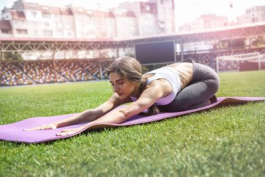 Şehir manzarası üzerinde paspas üzerinde egzersiz yapan genç bir kadın. Genç ve zayıf.