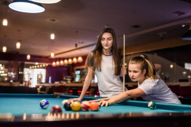 Pub 'da iki arkadaş. Günlük giysiler giyip bilardo oynuyorlar.