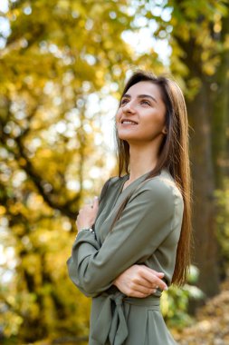 Kadın portresi. Sonbahar parkında zeytin rengi elbise giymiş esmer kadın portresi.