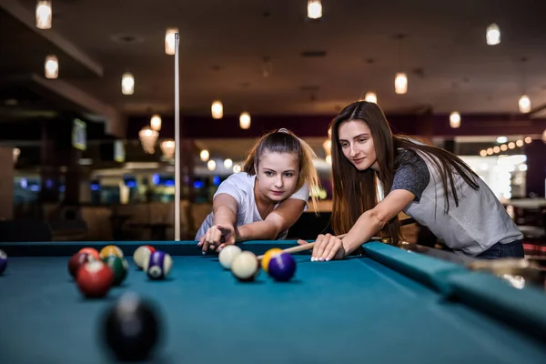 Two happy friends in pub playing billiard