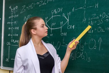 Kimyagerin sınıfında panoya yakın duran ve onu gösteren bir kadın.
