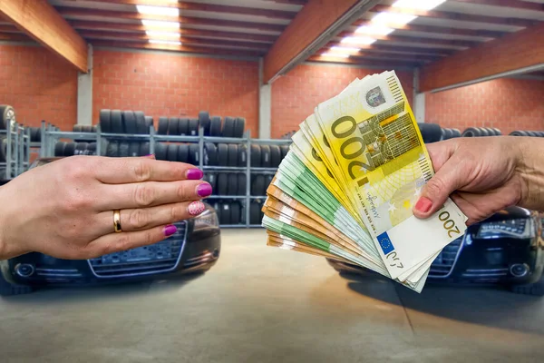 Close up view on female hands with euro banknotes against car garage and wheel stack