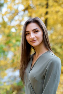 Kadın portresi. Sonbahar parkında zeytin rengi elbise giymiş esmer kadın portresi.