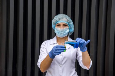 Mataralı kimyager bilimsel deney yapıyor. Koruyucu üniforma ve eldiven giyiyor.
