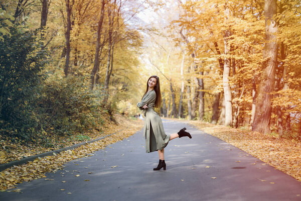 Autumn colours. Beautiful woman in coat posing in forest on roadside
