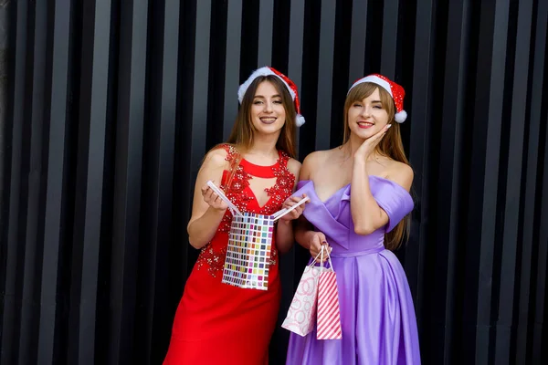 Duas Mulheres Incríveis Chapéus Santa Vestidos Noite Elegantes Segurando Sacos — Fotografia de Stock