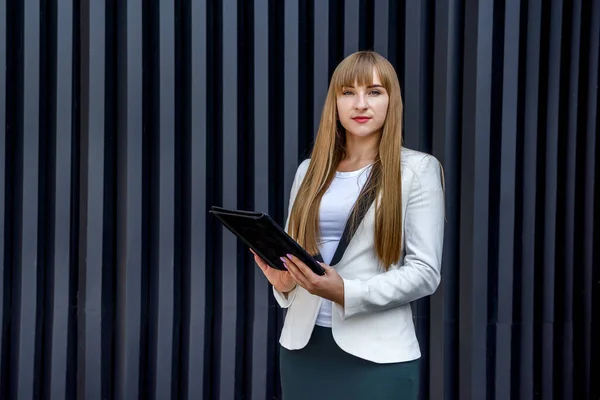 Portrait of young business woman with tablet over grey background