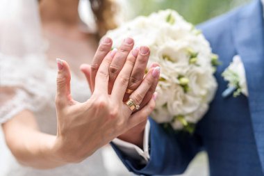 Düğün konsepti. Çiçek buketinde altın yüzüklerle erkek ve kadın eli