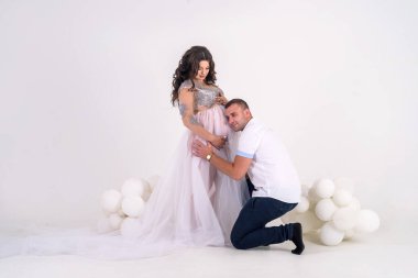 Pencerenin yanındaki stüdyoda poz veren inanılmaz çekici ve hamile çift.