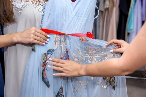 Female hands with red ribbon on the dress close up