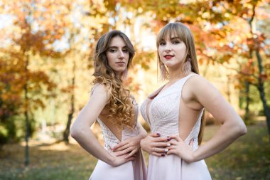 Sonbahar parkında güzel bej elbiseler giyen iki genç prenses. Moda fotoğrafı..