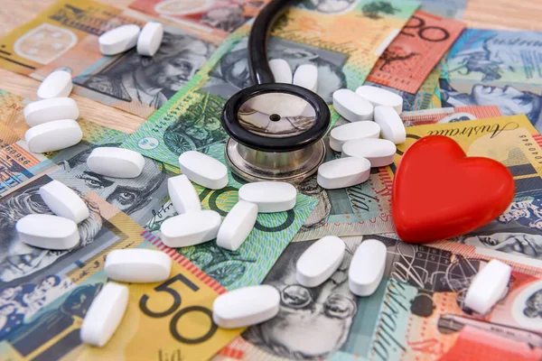Stethoscope with red heart and pills on australian dollars