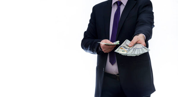 Человек в костюме на белом фоне показывает долларовые банкноты
