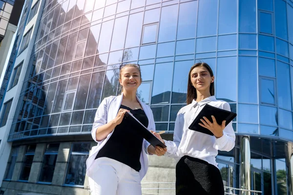 Young business woman signing contract outside business center in big city