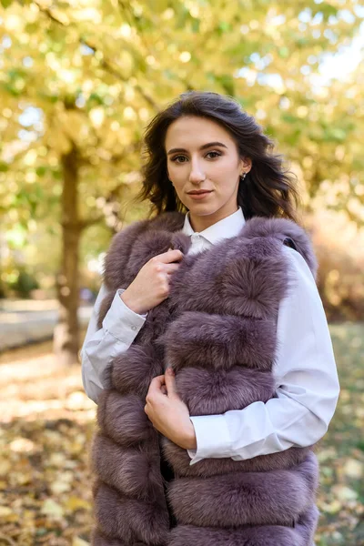 秋の公園を歩くファッショナブルな毛皮のコートを着た女性 — ストック写真