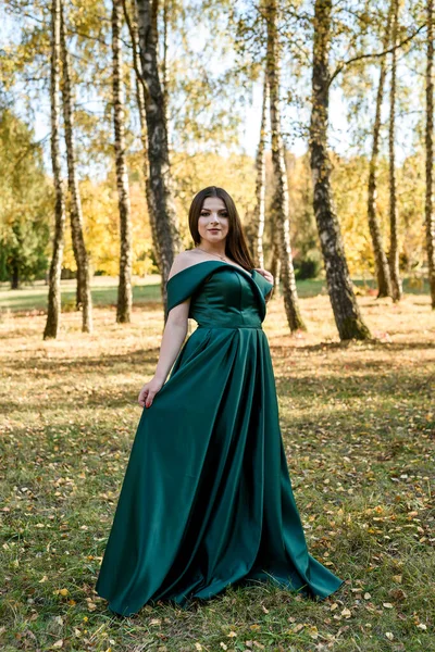 穿着时髦绿色衣服的年轻女子走在秋天的公园里 — 图库照片