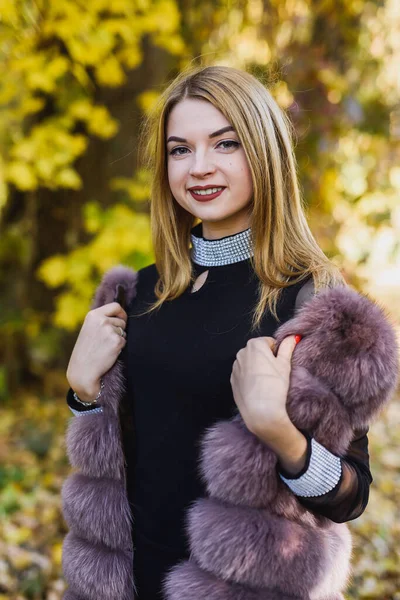 ファッションの女性 笑顔女の子で毛皮のコートのPosinで秋の公園で木とツタ — ストック写真