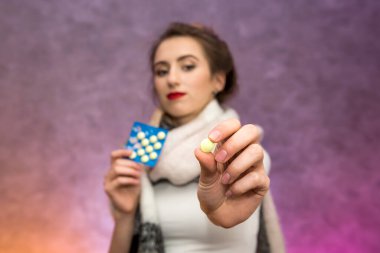 Boynunda sıcak atkısı olan yorgun bir kadın ve soyut arka planda poz veren su toplayan haplar. Hastalık konsepti