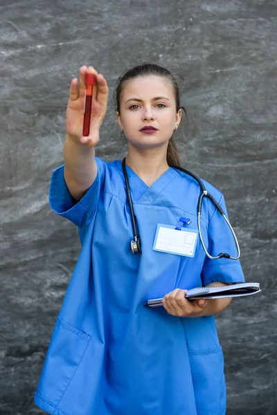 Pracownik Medyczny Trzymający Czerwoną Probówkę Patrzący Nią Laboratorium — Zdjęcie stockowe