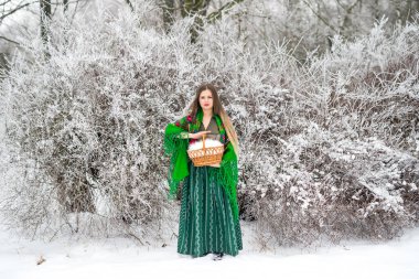 Beautiful woman with basket in winter forest